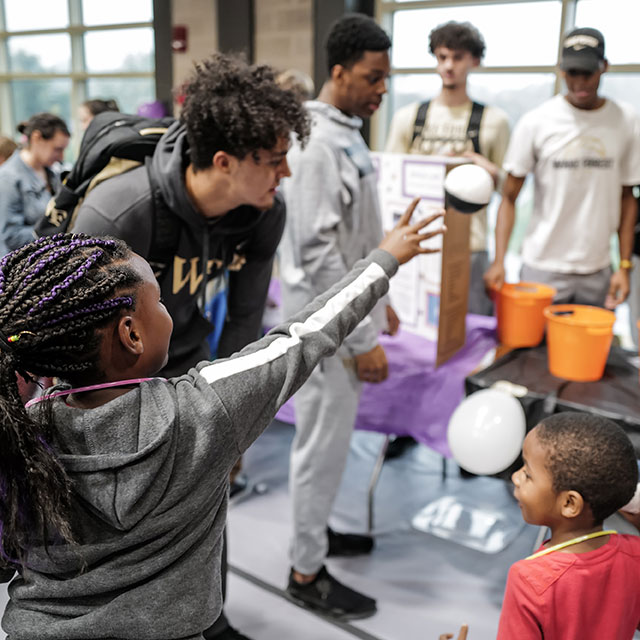 A student helps a child at a station