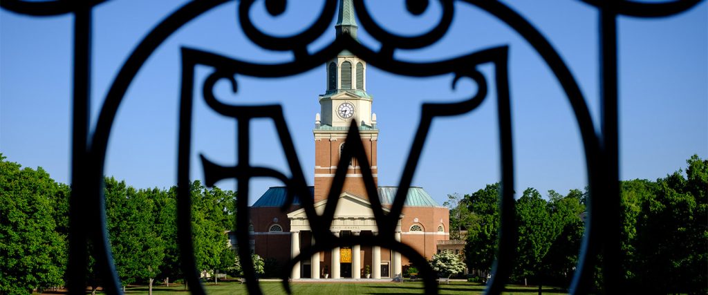 Wait Chapel is visible through an ironwork WF logo, on the campus of Wake Forest University.