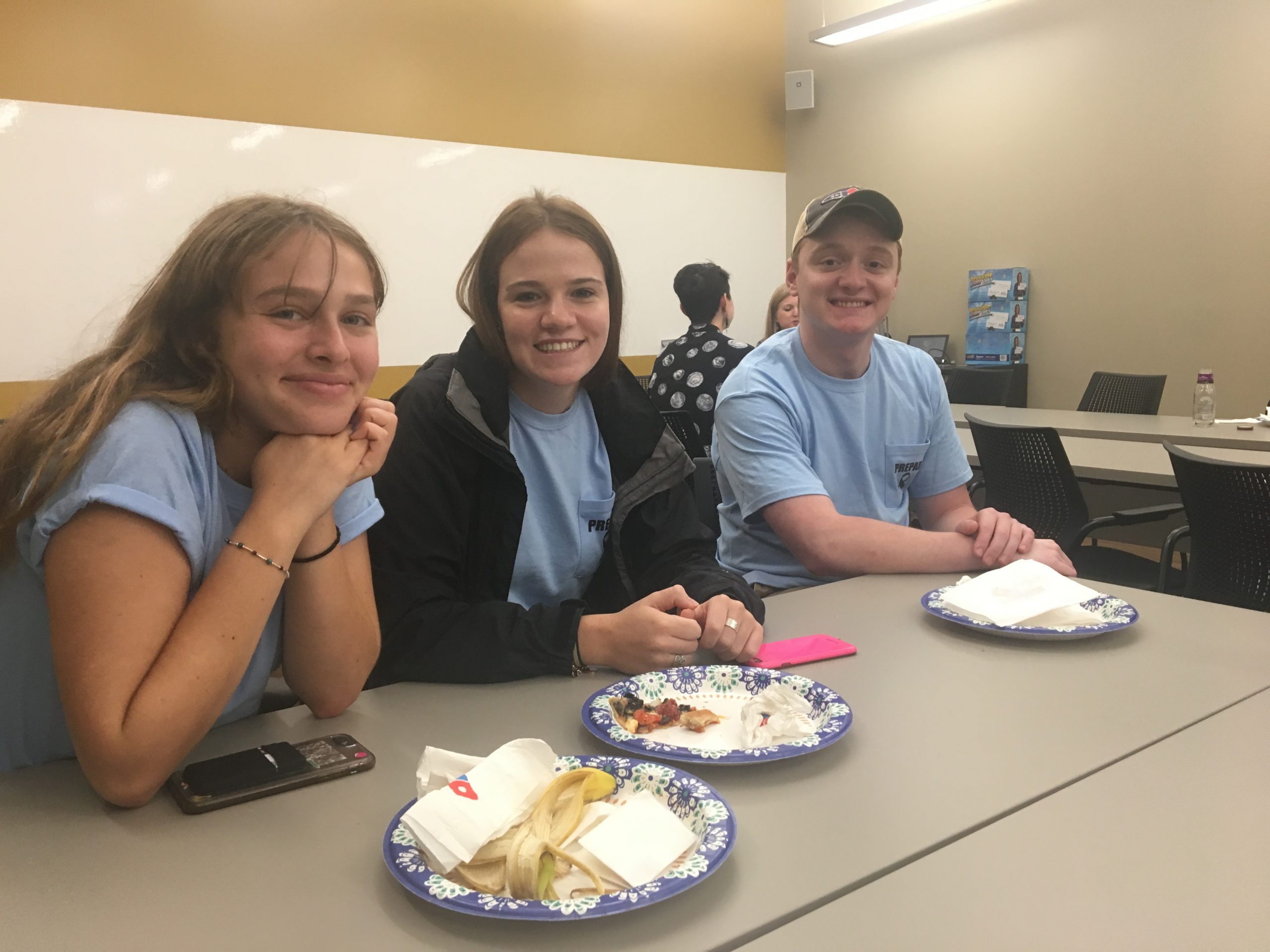 3 students smiling while sitting at a table