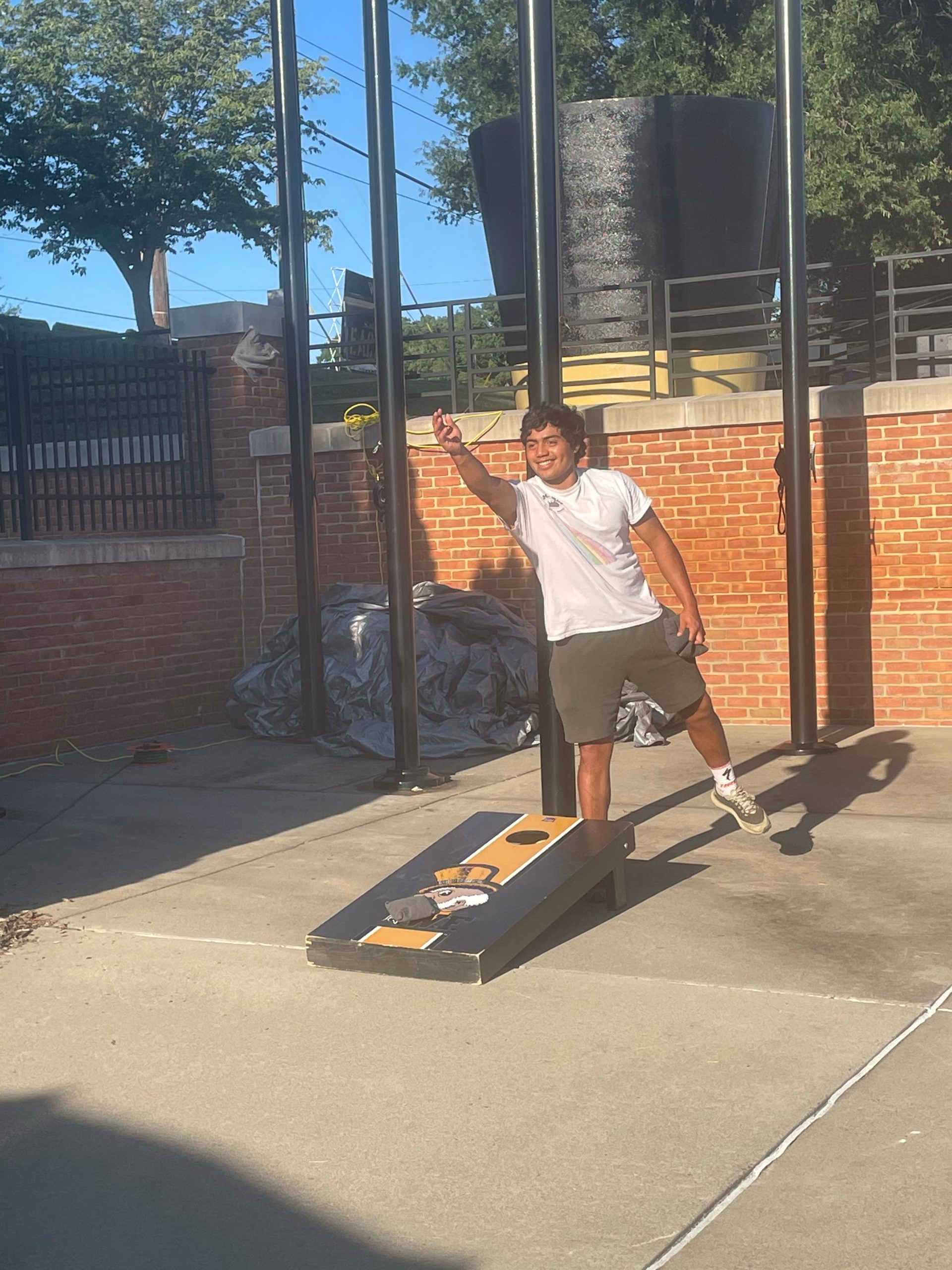 A student attendee playing bean bag toss during the tailgate