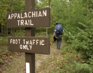 a hiker passes by a trail marker for the Appalachian Trail.