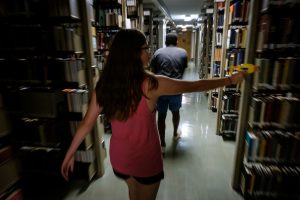 Students with NERF dart blasters search for zombies in the stacks of the ZSR Library