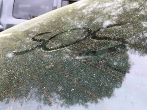 A witty SOS note written in pollen on a car