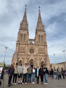 a picture from Professor Jones & the Wake Forest in Buenos Aires trip where nine students are currently studying Organic Chemistry 2 with Professor Jones. This picture is from Lujan Buenos Aires and one of the students has a WFU hat on