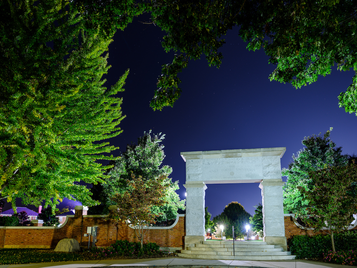 The archway leading to Hearn Plaza is lit at night, on the campus of Wake Forest University, Wednesday, October 7, 2020.