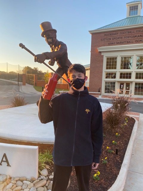 Hopeful future student at the statue of the Deacon. Both are masked.