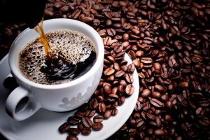 Mug on plate filled with coffee surrounded by coffee beans