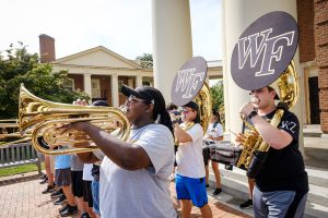 Members of the Wake Forest community participate in the annual Hit the Bricks for Brian cancer research fundraiser on Hearn Plaza on Thursday, September 30, 2021. More than 1700 people ran and walked around the quad to raise money. The marching band performs in front of Wait Chapel.