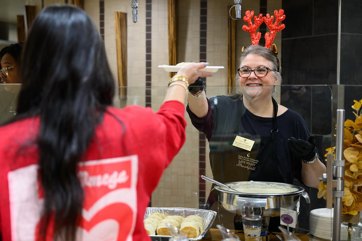 Dr. Betsy Chapman of Communications and External Relations serves biscuits and gravy at the Late Night Breakfast 12/6/23 