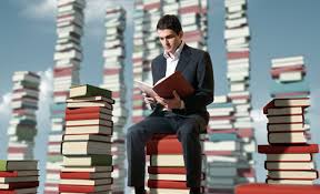 Man sitting on books and reading