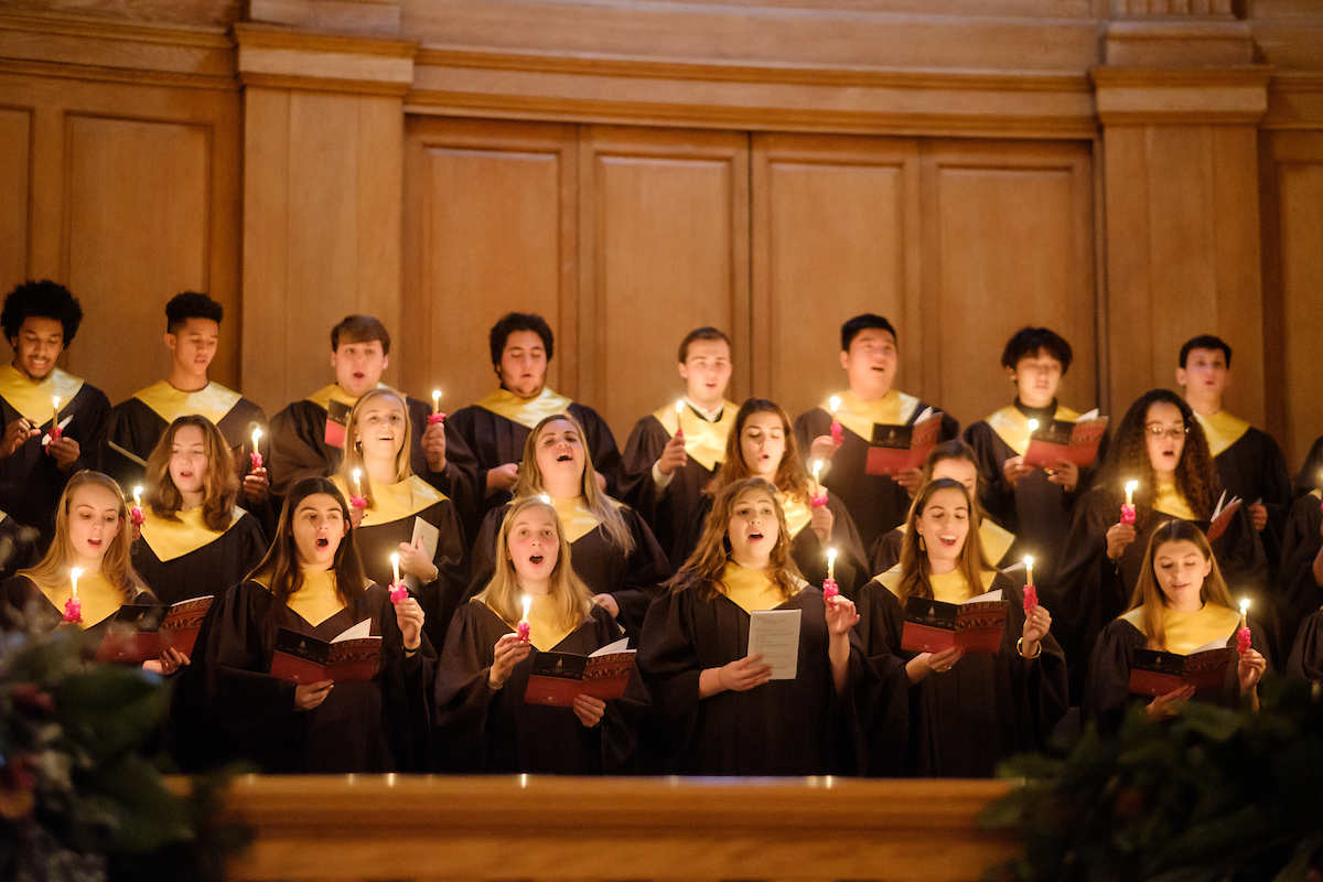 choir members sing while holding candles in wait chapel