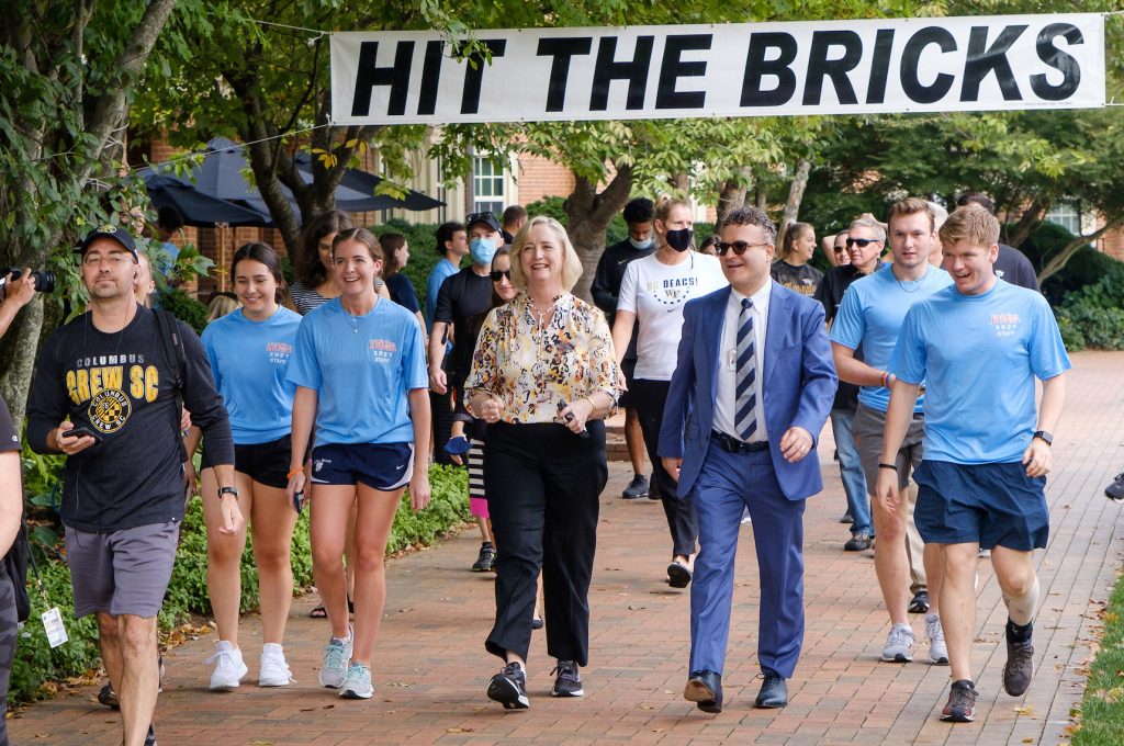 President Wente walking with student organizers under the Hit the Bricks sign.