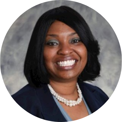 Bonita Brown headshot, she has chin length, dark hair. She is wearing a suit and a pearl necklace, and a smile!