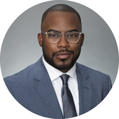 Headshot of Kevin Smith, he is wearing a light blue/gray suit and clear rimmed glasses.