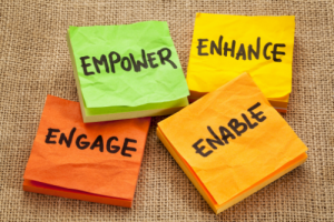 Four sticky notes with the words Empower, Engage, Enhance, and Enable written on them