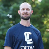 Headshot of Drew Dayton, he is smiling and wearing a school shirt