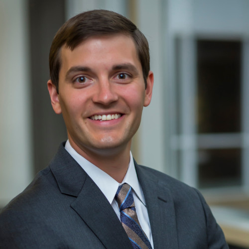 Headshot of Ryan Smith, he is wearing a suit and a big smile