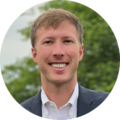 Head shot of Corey Pegram. He is wearing a button-down and suit jacket, and a smile.