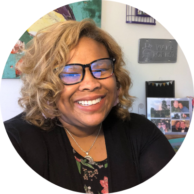 Headshot of Kim Jones, she is a Black woman with short blonde curly hair, wearing a black shirt and a big smile