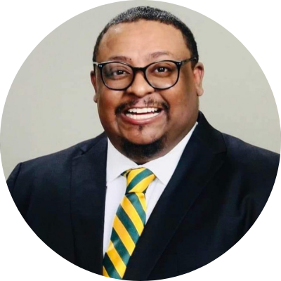 Headshot of Charles Gibson, he is a Black man with short hair, wearing a suit, green and yellow tie, and a smile.