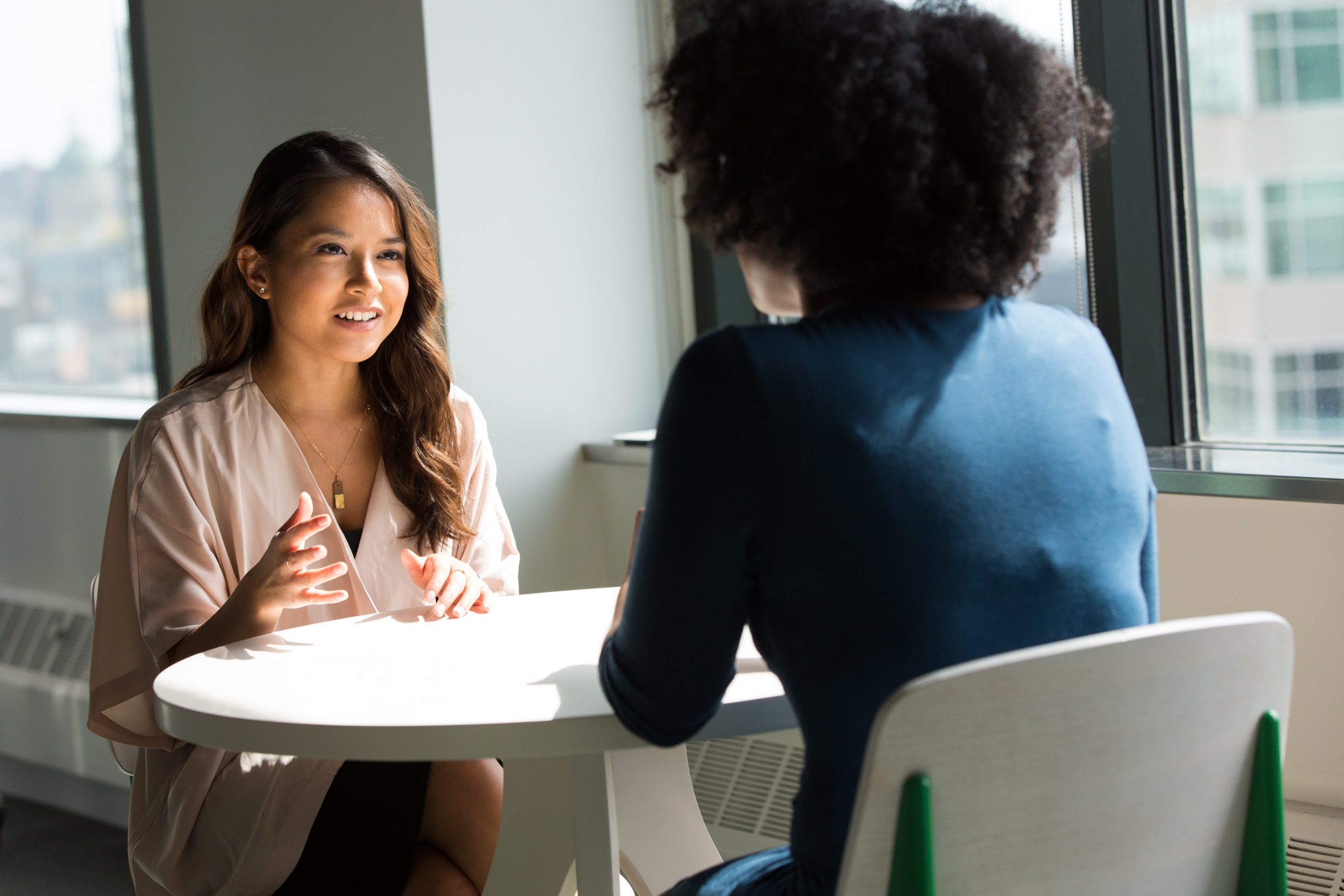 Two women talking and seated across from one another at a small circle