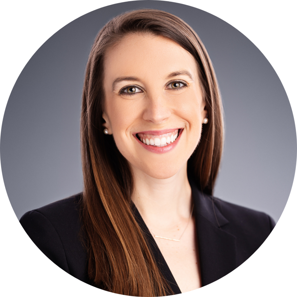 Headshot photo of woman smiling with long brown hair in black business suit.