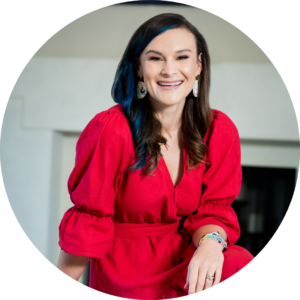 Woman with dark hair and a red dress smiling for a headshot photo