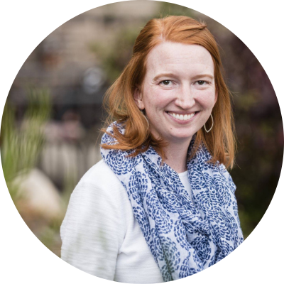 Woman with red hair and a blue scarf smiling at the camera