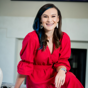 Woman with dark hair in a red dress smiling at the camera