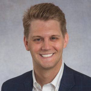 Man with blonde hair in a suit smiling at the camera