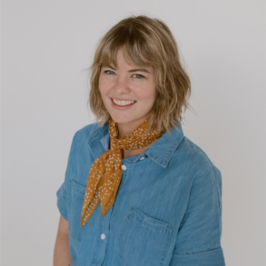 Woman with short hair and a blue shirt smiling at the camera