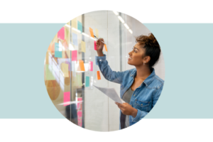 Woman writing on a glass wall surrounded with colorful sticky notes