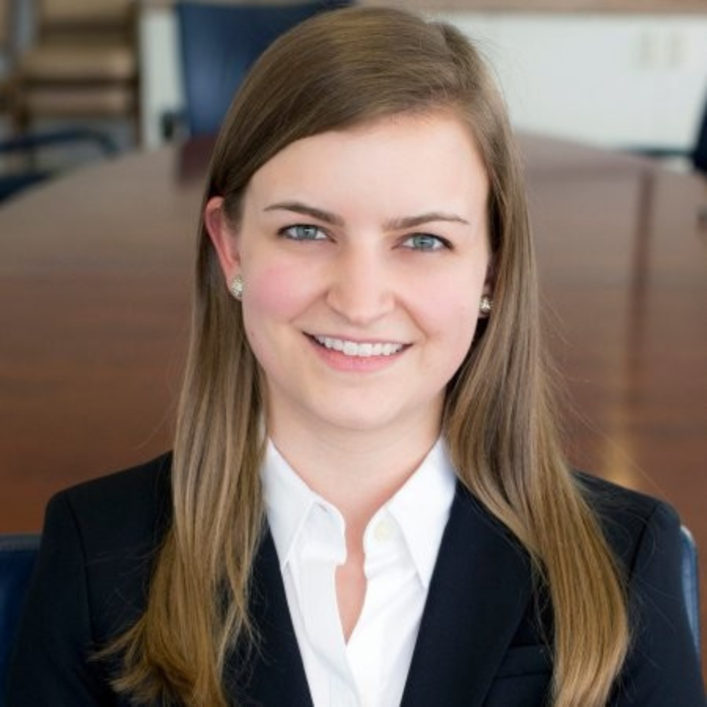 Photo of a woman wearing a white shirt and a black blazer smiling at the camera