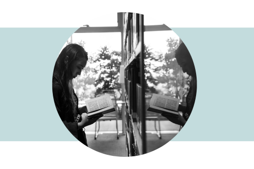 Greyscale image of a woman reading a book with her image reflected