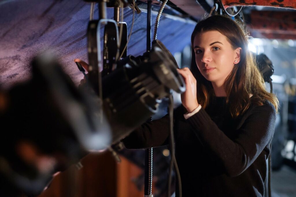Lainey Drake ('22), a physics and theatre major, works on the lights for a main stage theatre performance, in Scales Fine Arts Center.