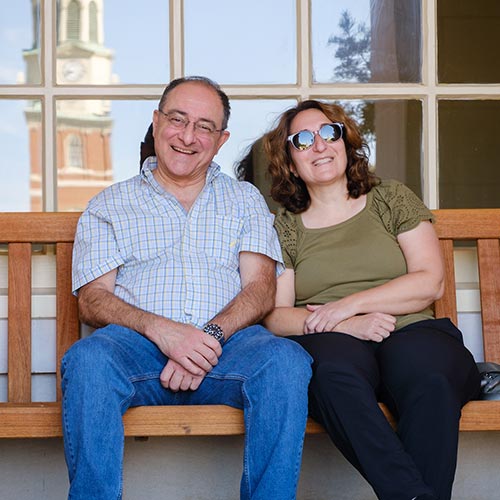 Parents relaxing on a bench outside of Reynolda Hall