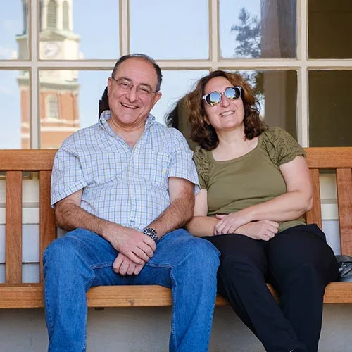 Parents relaxing on a bench outside of Reynolda Hall