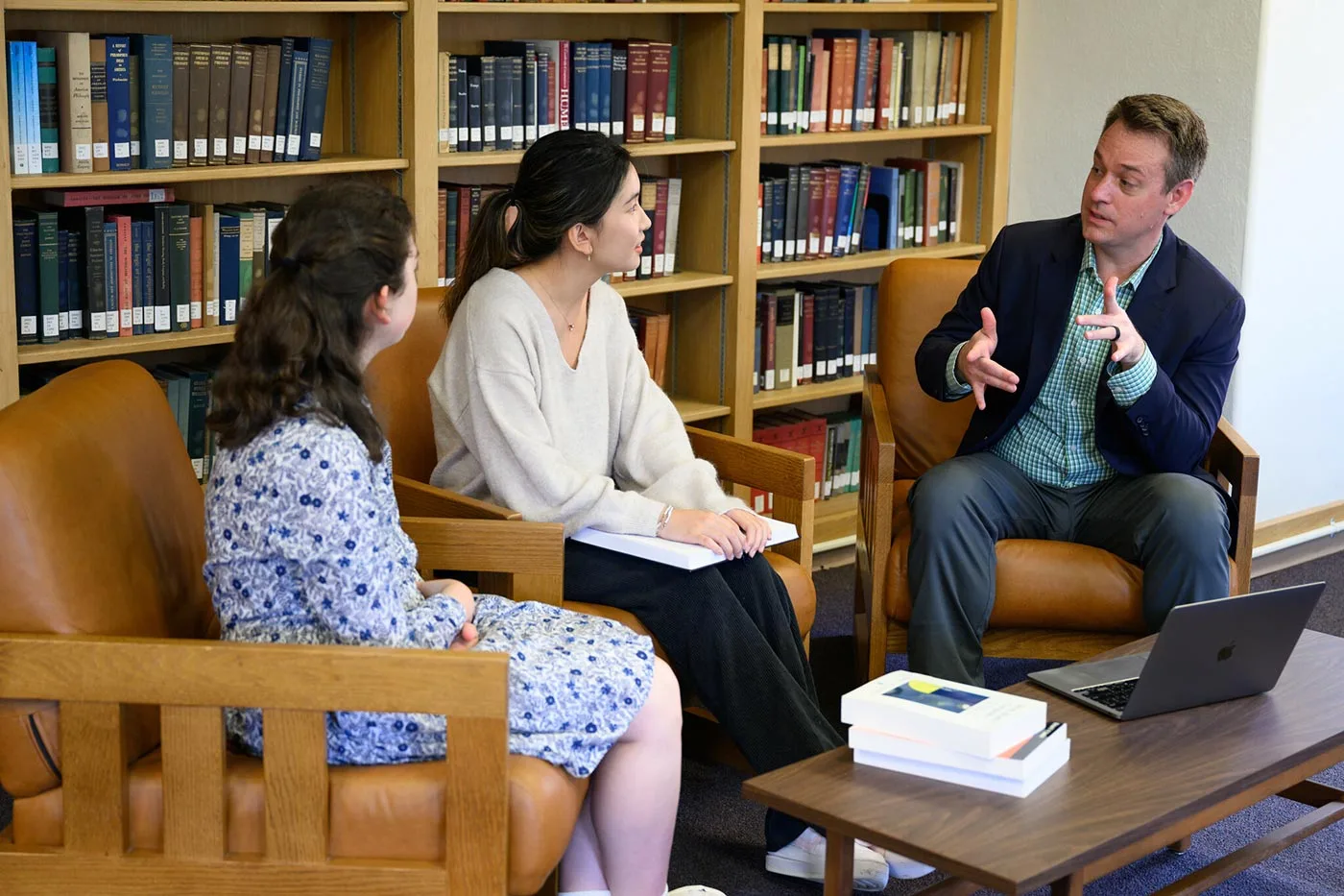 Philosophy Prof. Amanda Corris and Tobias Flattery discuss the ethical aspects to artificial intelligence with a student in the Philosophy Library in Tribble Hall.