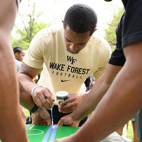 Wake Forest University students paint desks alongside local school children at Davis Field.