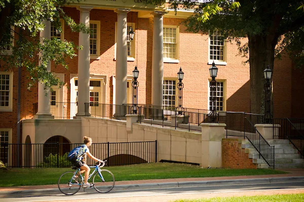 Student riding a bicycle across campus