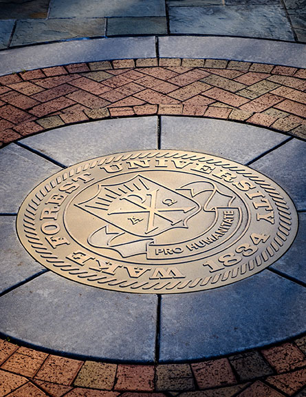 The University Seal is embedded in the brick sidewalk in front of Alumni Hall, on the campus of Wake Forest University, Monday, March 8, 2021.