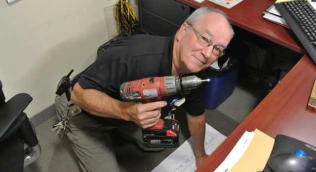 Hugh, one of our technicians, performing maintenance ion an office setting with his power drill