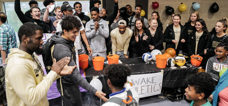 Students at the Wake Forest Athletic's Booth cheers on child after successfully completing a task at the 2019 Project Pumpkin event.