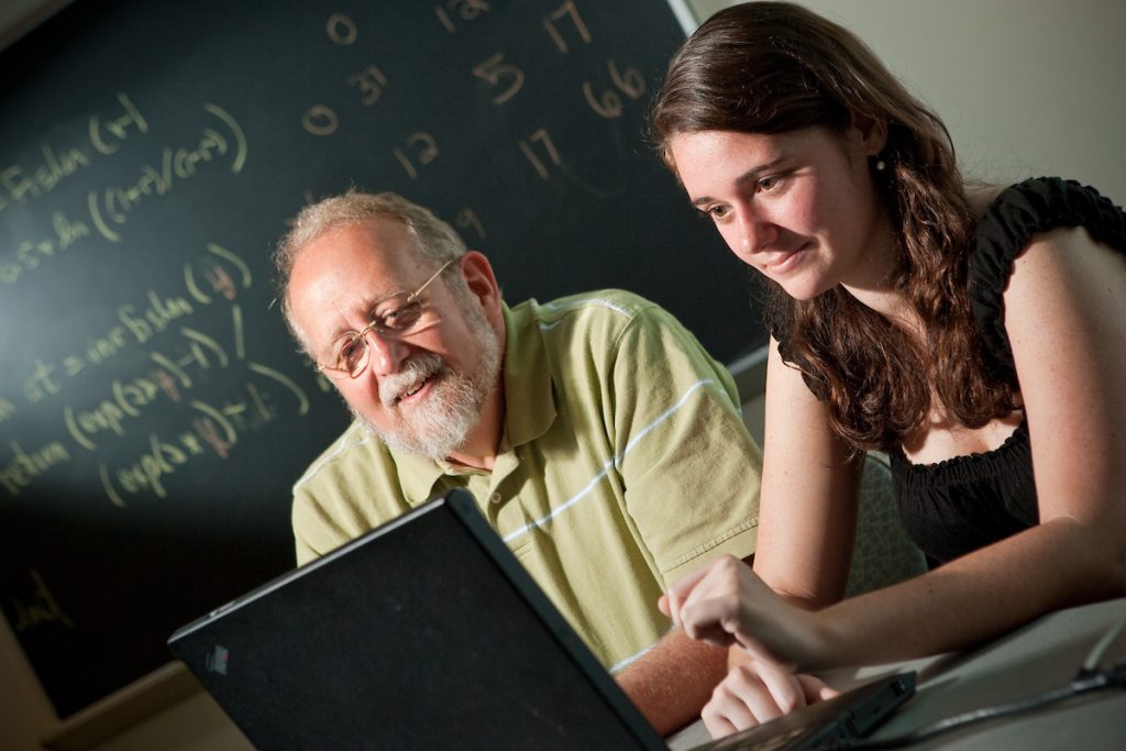 David John looks at a computer with student Rachel Black