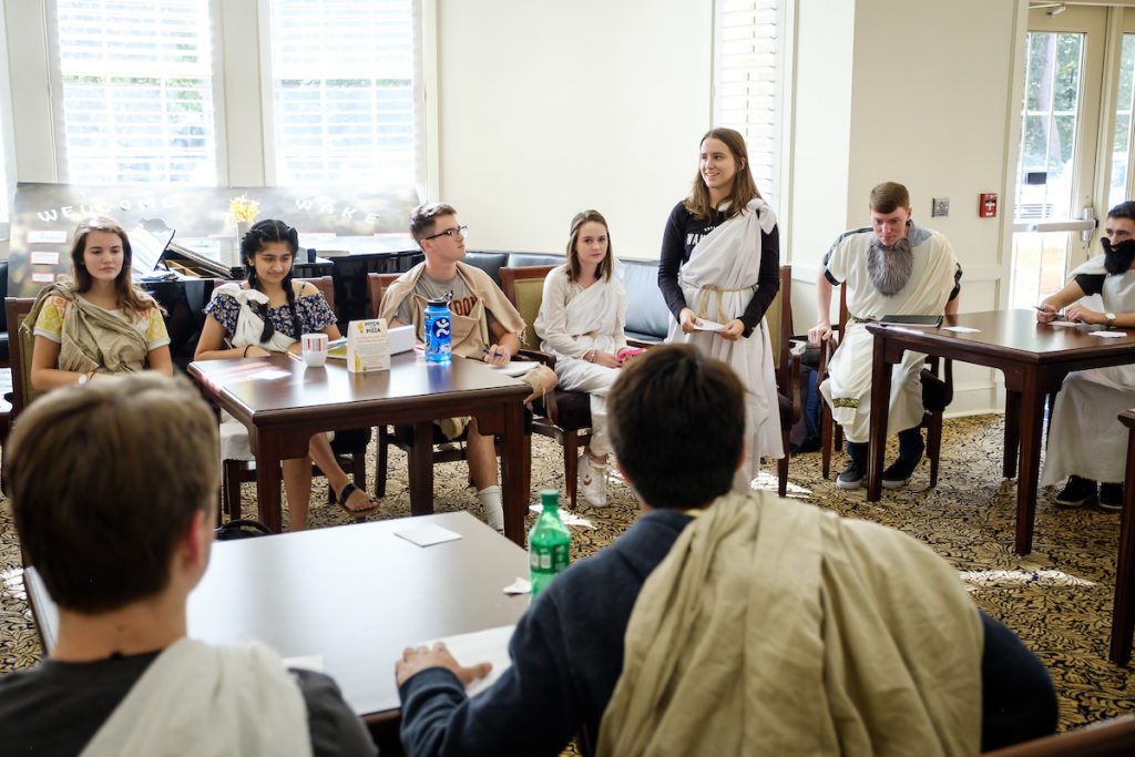 Students wear togas inside a classroom set up as a trial.