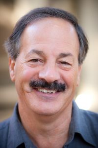 Professor Robert Browne smiles at the camera wearing a blue collared shirt.