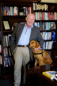 Allan Louden poses in in Carswell Hall with his Golden retriever, Glacier,