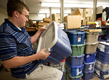 Andrew McCarty ('12) rearranges boxes of evidence in the debate storage room.