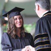 President Hatch shakes hands with a graduate.