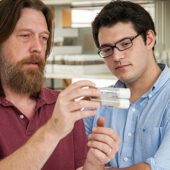 Erik Johnson examines test tubes with graduate student Jason Braco.